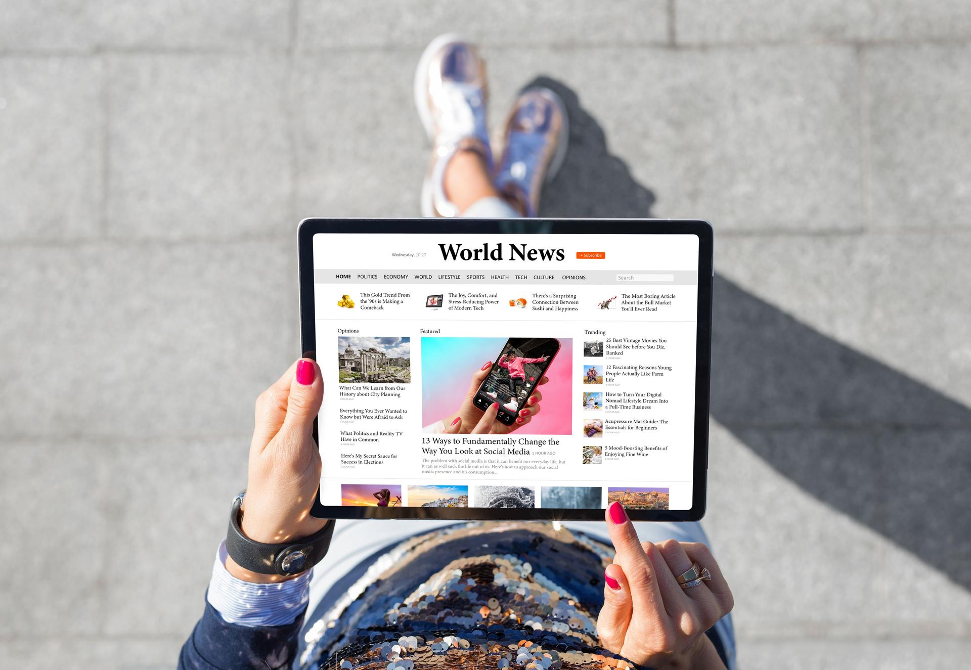 Woman standing outdoors and reading news on tablet computer