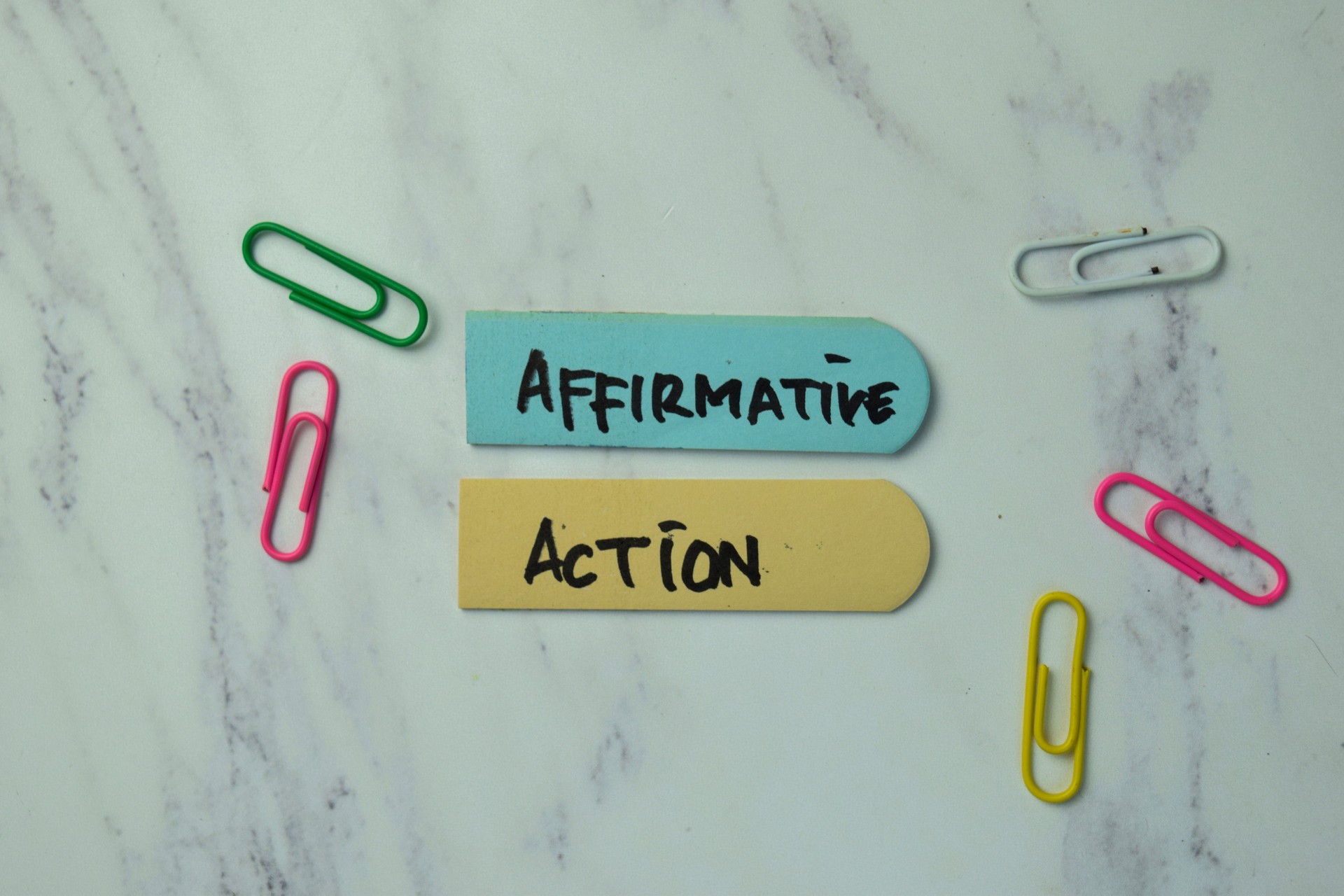 Affirmative Action write on sticky notes isolated on office desk.